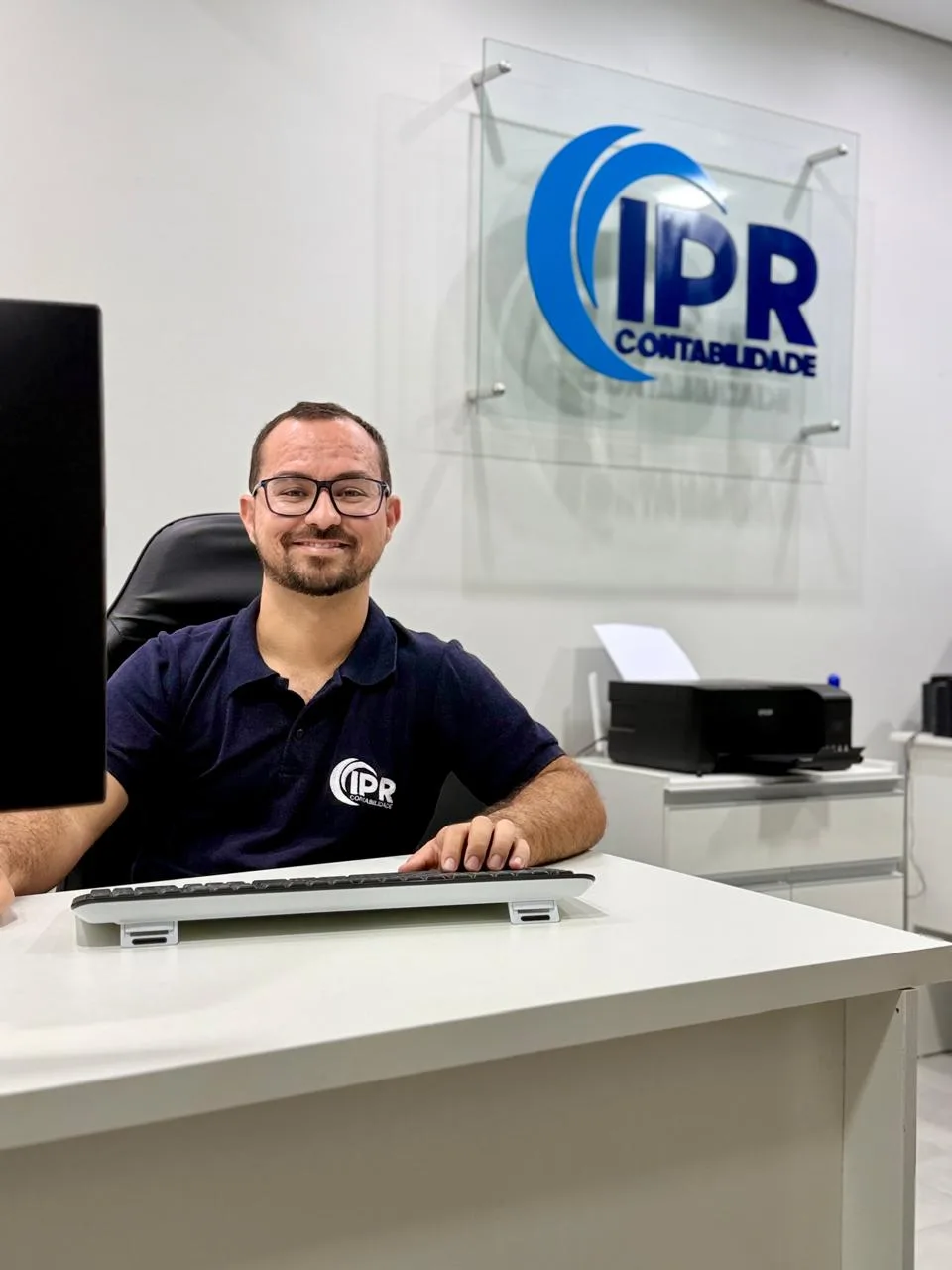 Proprietário da IPR Contabilidade em seu atendimento no escritório, com a logo da IPR Contabilidade na parede